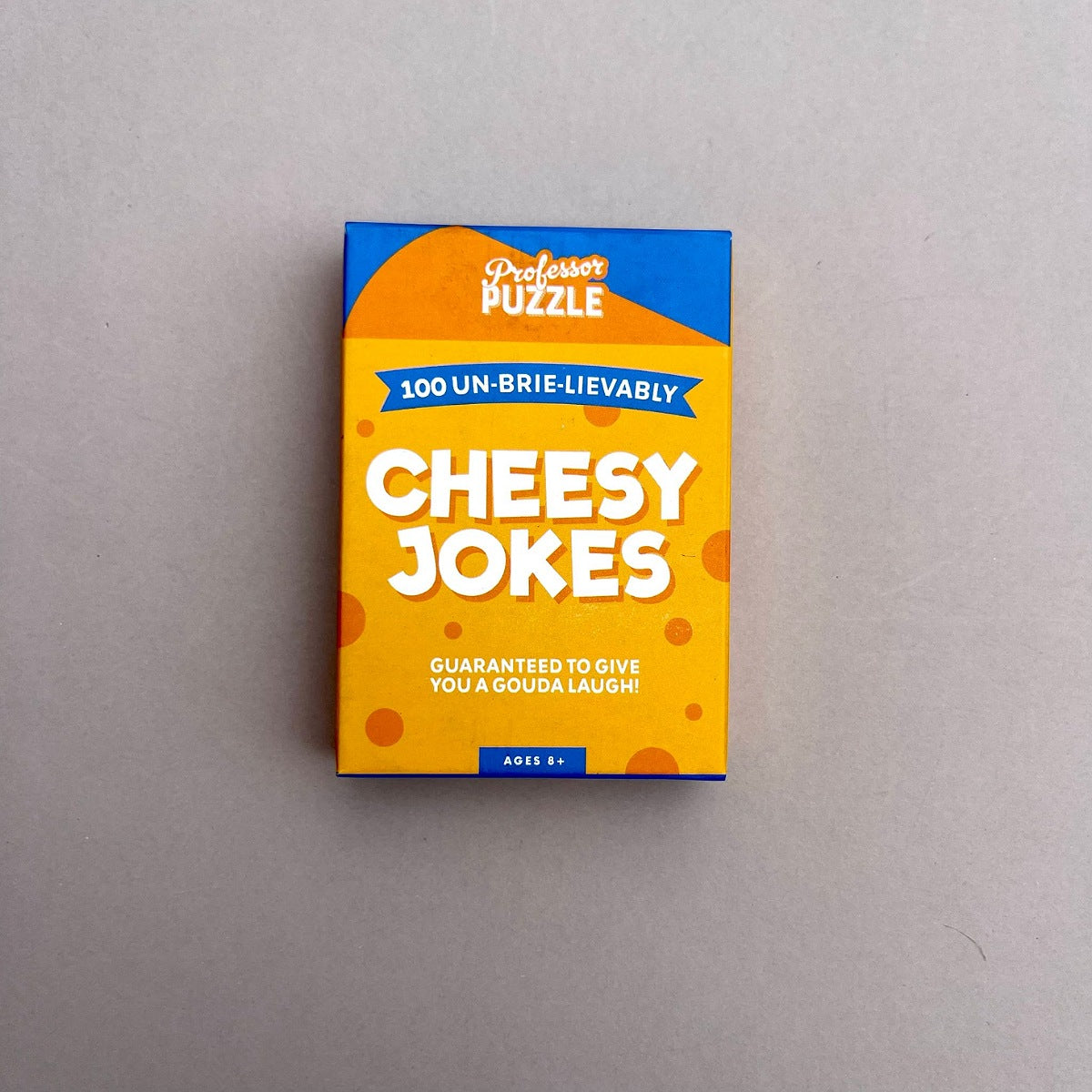 Box of 'Cheesy Jokes' on a grey background