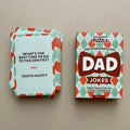 A box and a stack of cards on a plain beige surface. The box reads "Professor Puzzle" and "Dad Jokes," with a retro argyle pattern in mint green, coral, and white.