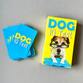 A stack of blue cards on a plain beige background with a box that is yellow with large blue and white text reading 'DOG IQ Test' and a photo of a dog wearing glasses.