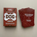 Brown box for 'Dog Jokes' with a stack of cards on a beige background