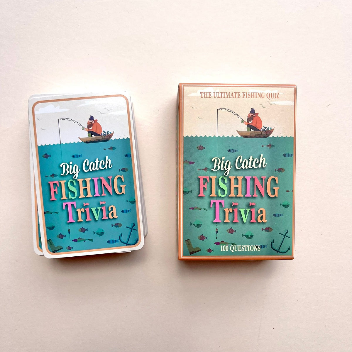 A set of cards and matching box labelled "Big Catch Fishing Trivia" with illustrated man fishing on a boat with various fish under water, photographed on a plain beige background.