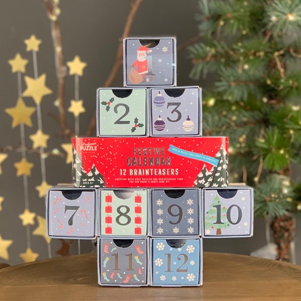 Stack of advent calendar boxes with festive designs on a wooden surface.