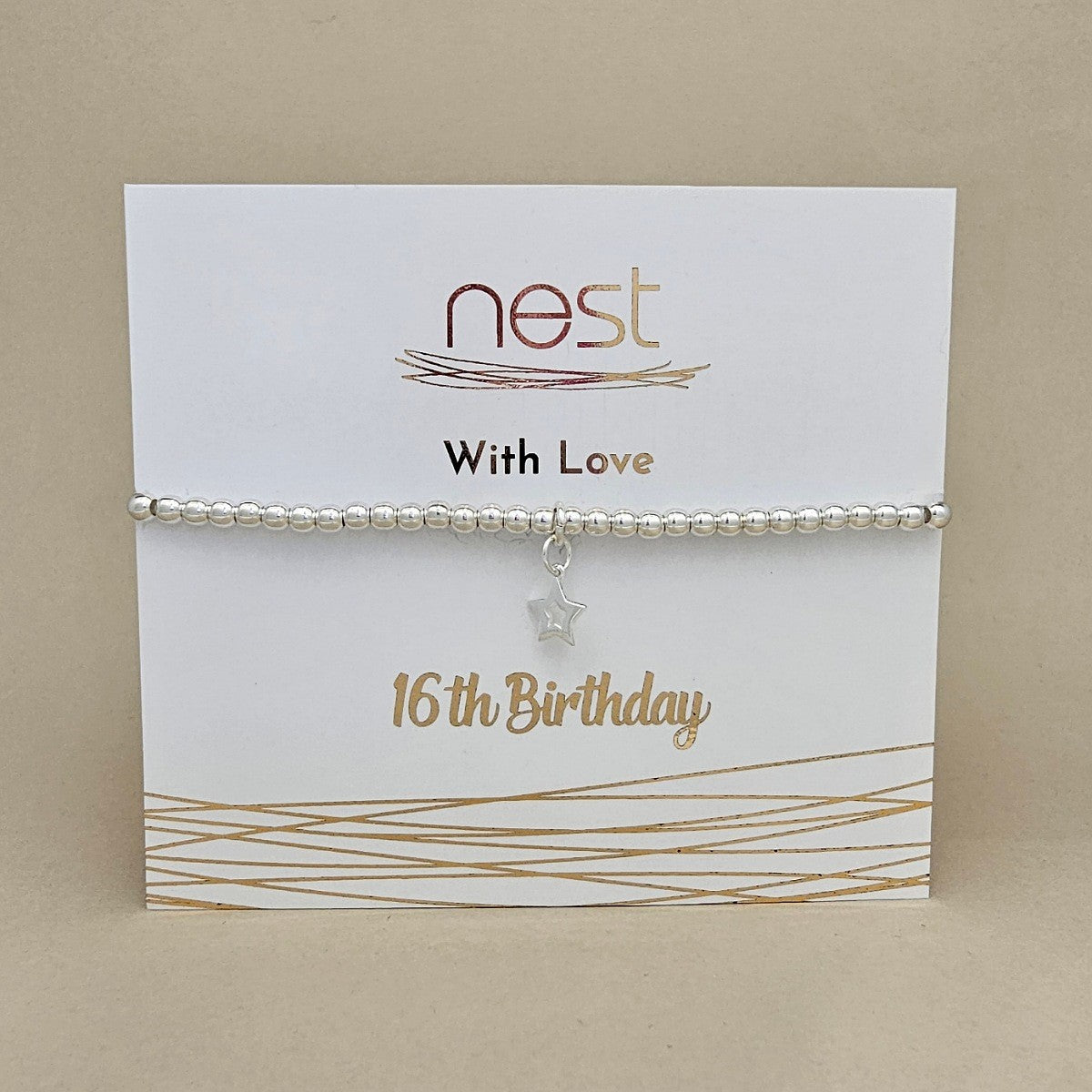A silver beaded bracelet with a small star charm, displayed on a white card that reads 'nest With Love 16th Birthday' against a beige background.