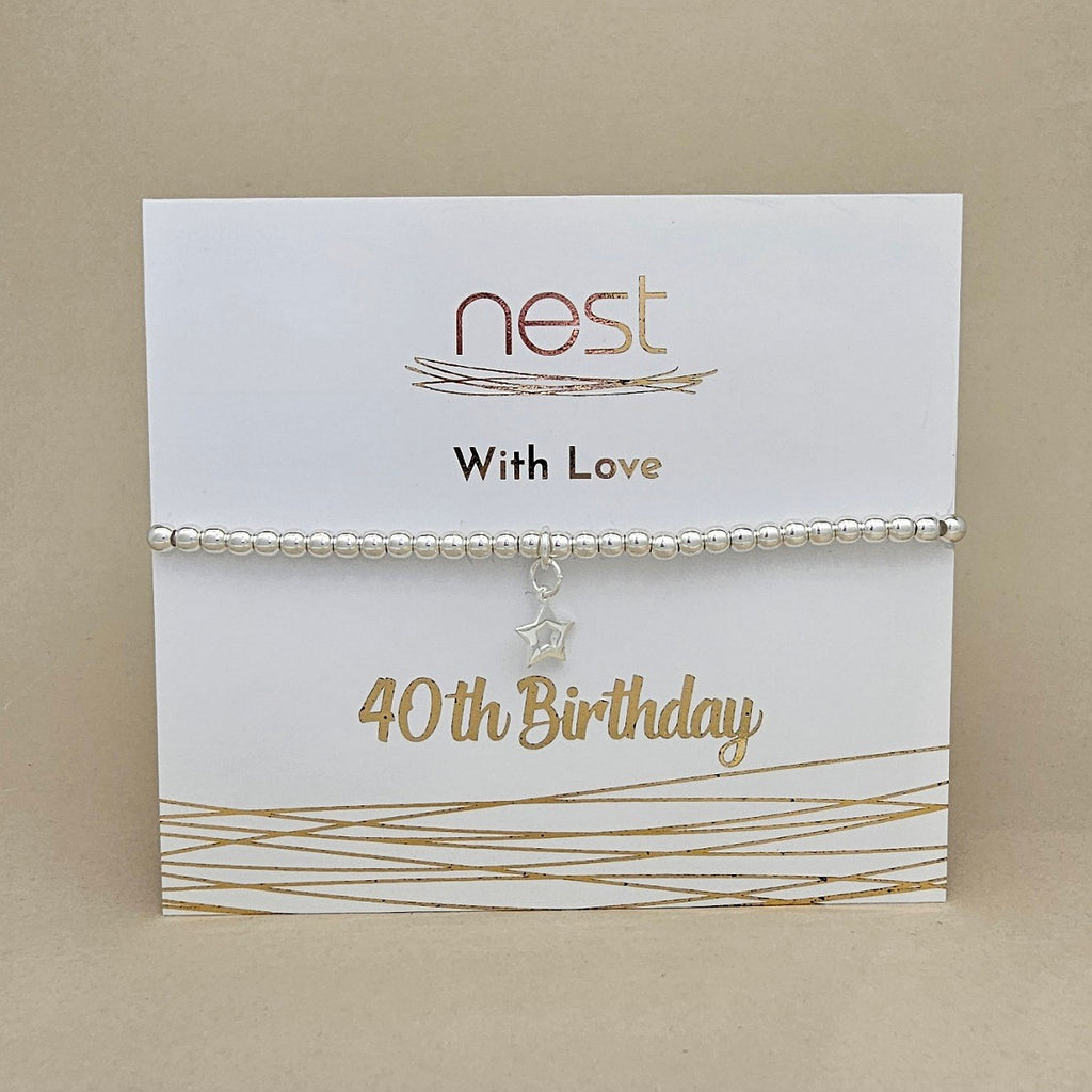 A silver beaded bracelet with a dangling star charm, displayed on a white card that reads 'nest With Love 40th Birthday' against a beige background.