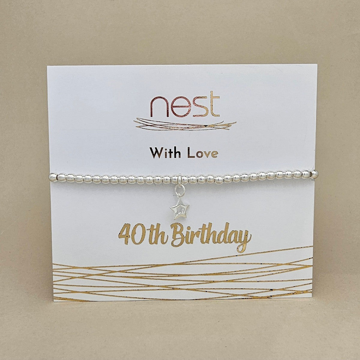 A silver beaded bracelet with a dangling star charm, displayed on a white card that reads 'nest With Love 40th Birthday' against a beige background.