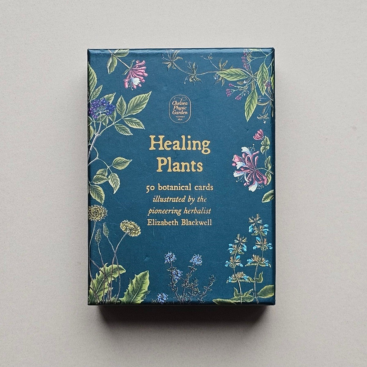 Box of 'Healing Plants' botanical cards with floral design on a grey background