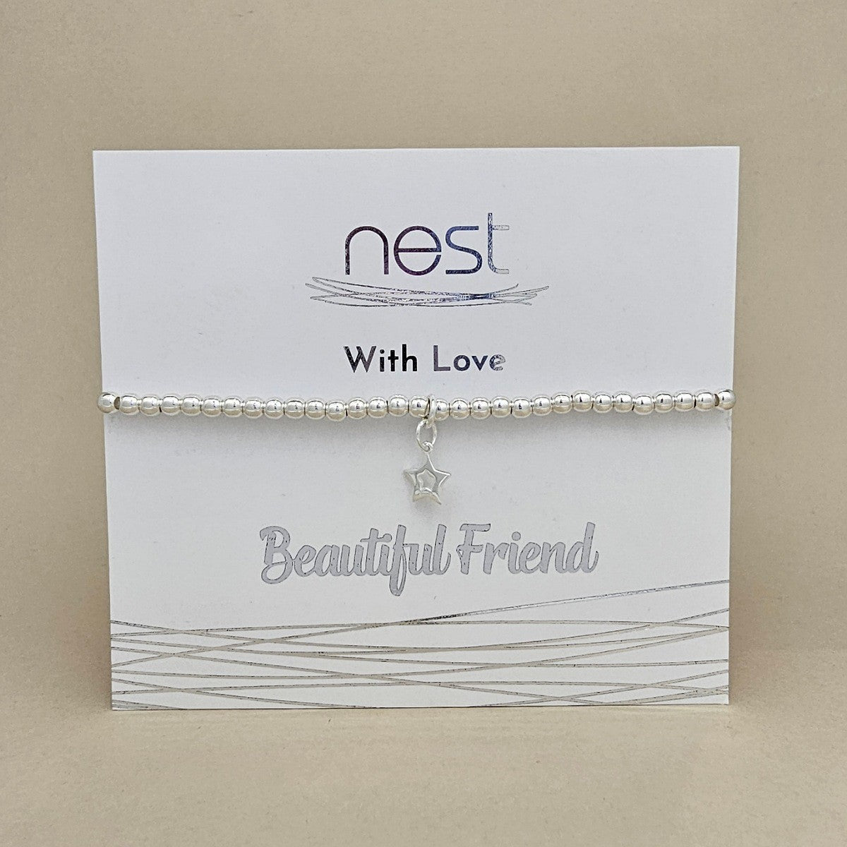 A silver beaded bracelet with a dangling star charm, presented on a white display card branded 'nest' with the words 'With Love' and 'Beautiful Friend'.