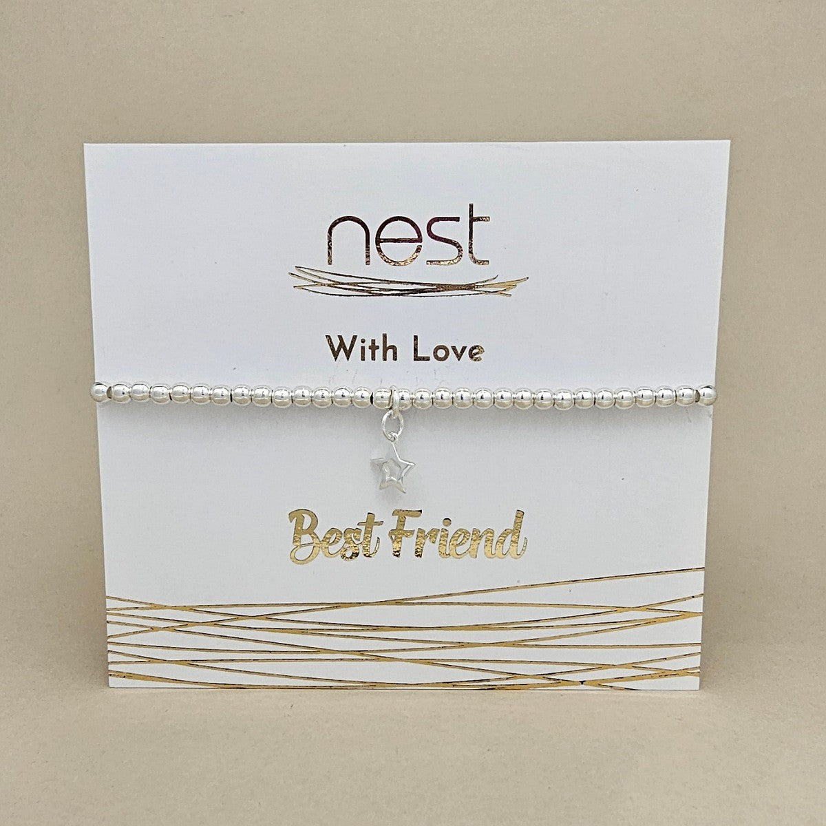 A silver beaded bracelet with a small star charm, presented on a white display card with gold foil accents and the text 'nest With Love Best Friend'.