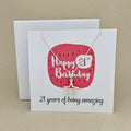 A silver open star necklace displayed on a white card with a bright pink rounded square and the text 'Happy 21st Birthday' and ’21 years of being amazing,' 