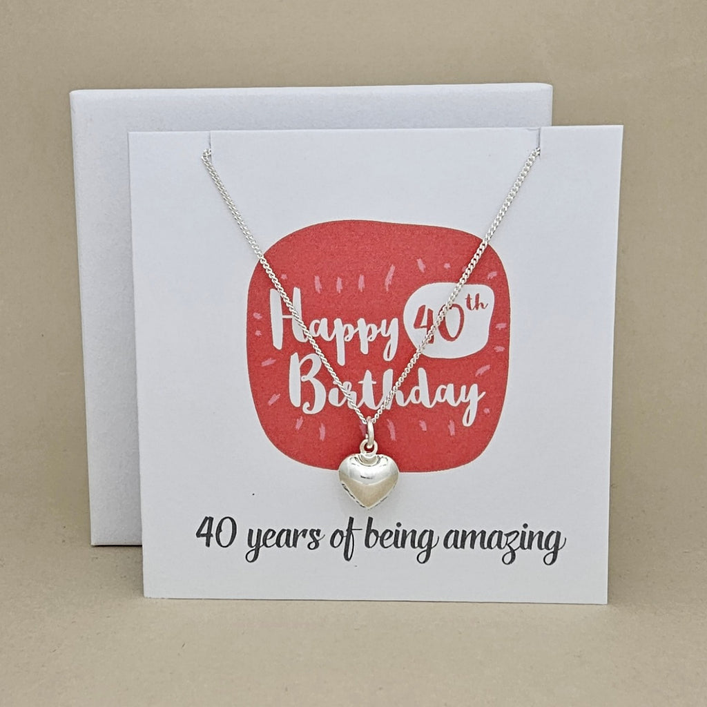 A silver heart necklace displayed on a white card with a red rounded square and the text 'Happy 40th Birthday' and ’40 years of being amazing,'
