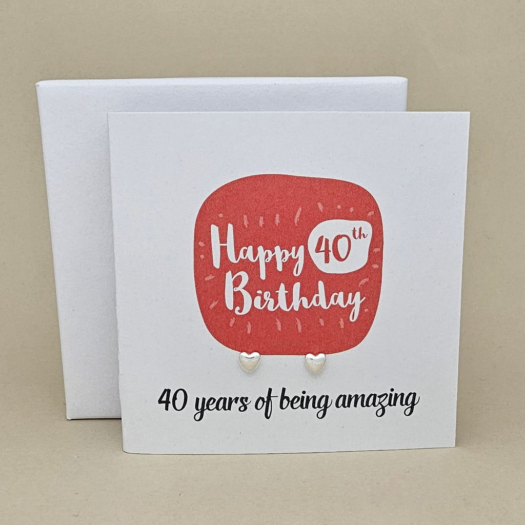 A pair of silver heart earrings displayed on a white card with a red rounded square and the text 'Happy 40th Birthday' and ’40 years of being amazing,'
