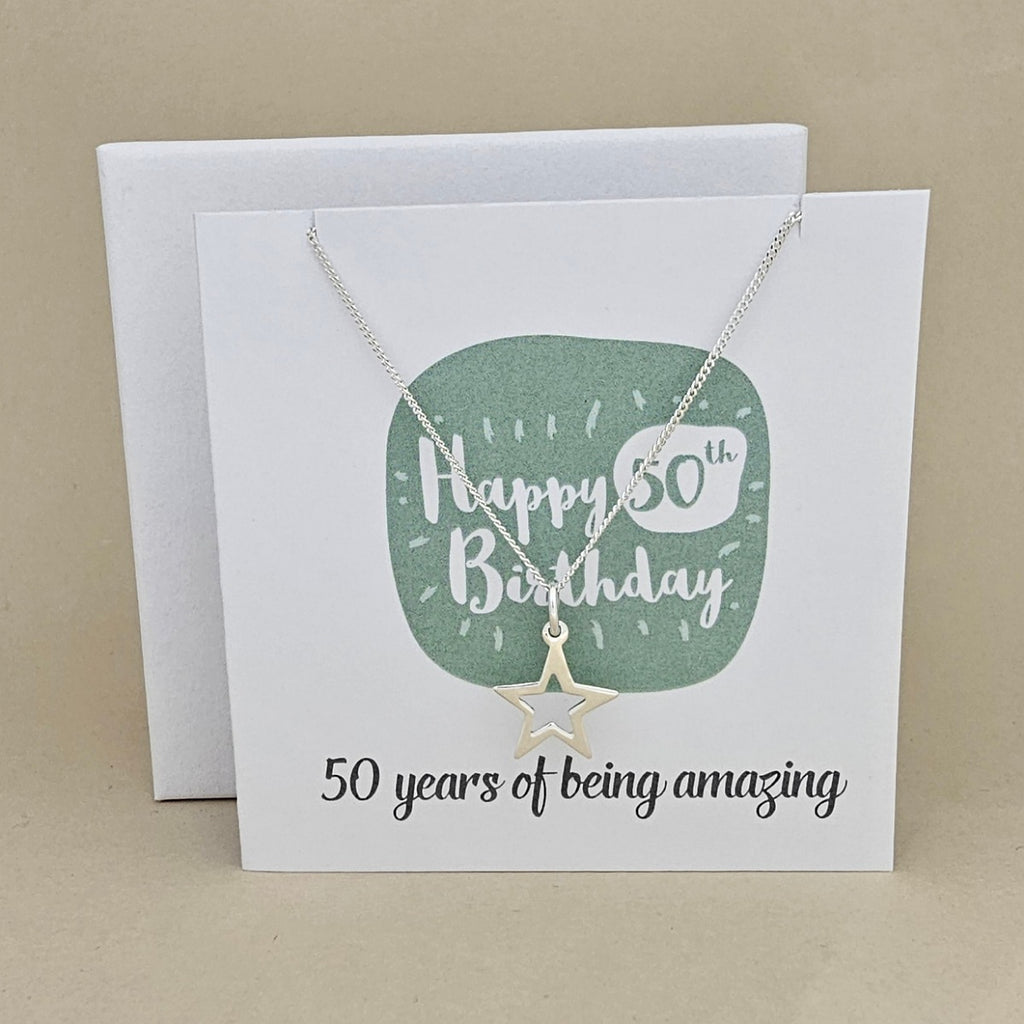 A silver open star necklace displayed on a white card with a green rounded square and the text 'Happy 50th Birthday' and ’50 years of being amazing,'
