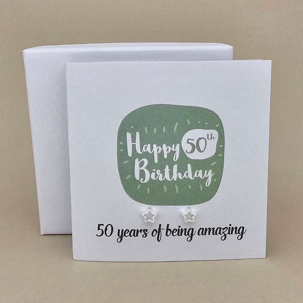 A pair of silver open star earrings displayed on a white card with a green rounded square and the text 'Happy 50th Birthday' and ’50 years of being amazing,'
