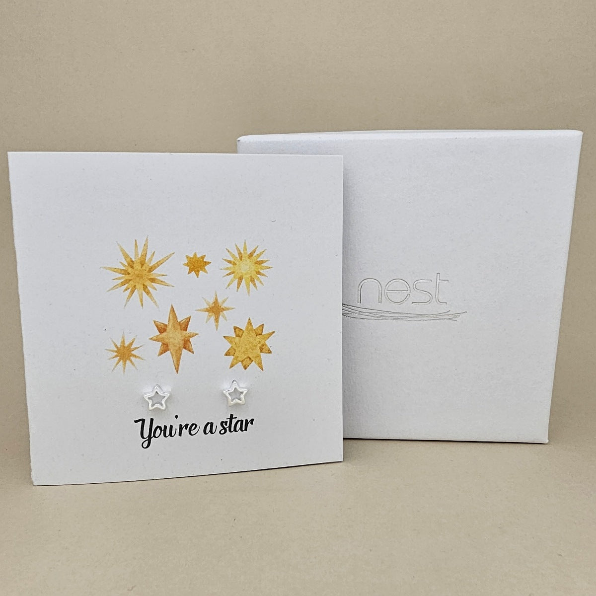Card with star designs and silver earrings with 'You're a star' text, next to a box labelled 'nest'.