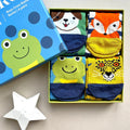 Four brightly coloured children's socks folded in a presentation box with a lid with a green frog and blue circle patterns on it.  Each sock with a different animal face design: a dog on a green sock with blue paw prints, a green frog on a blue sock with navy spots, a yellow leopard with navy print, and a orange fox on a navy-and-white stripe sock.