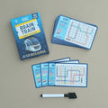 Brain Train Logic Puzzles set on a neutral beige background, showing the blue retail box, a stack of blue puzzle cards, several individual cards laid out, and a white-and-black marker.