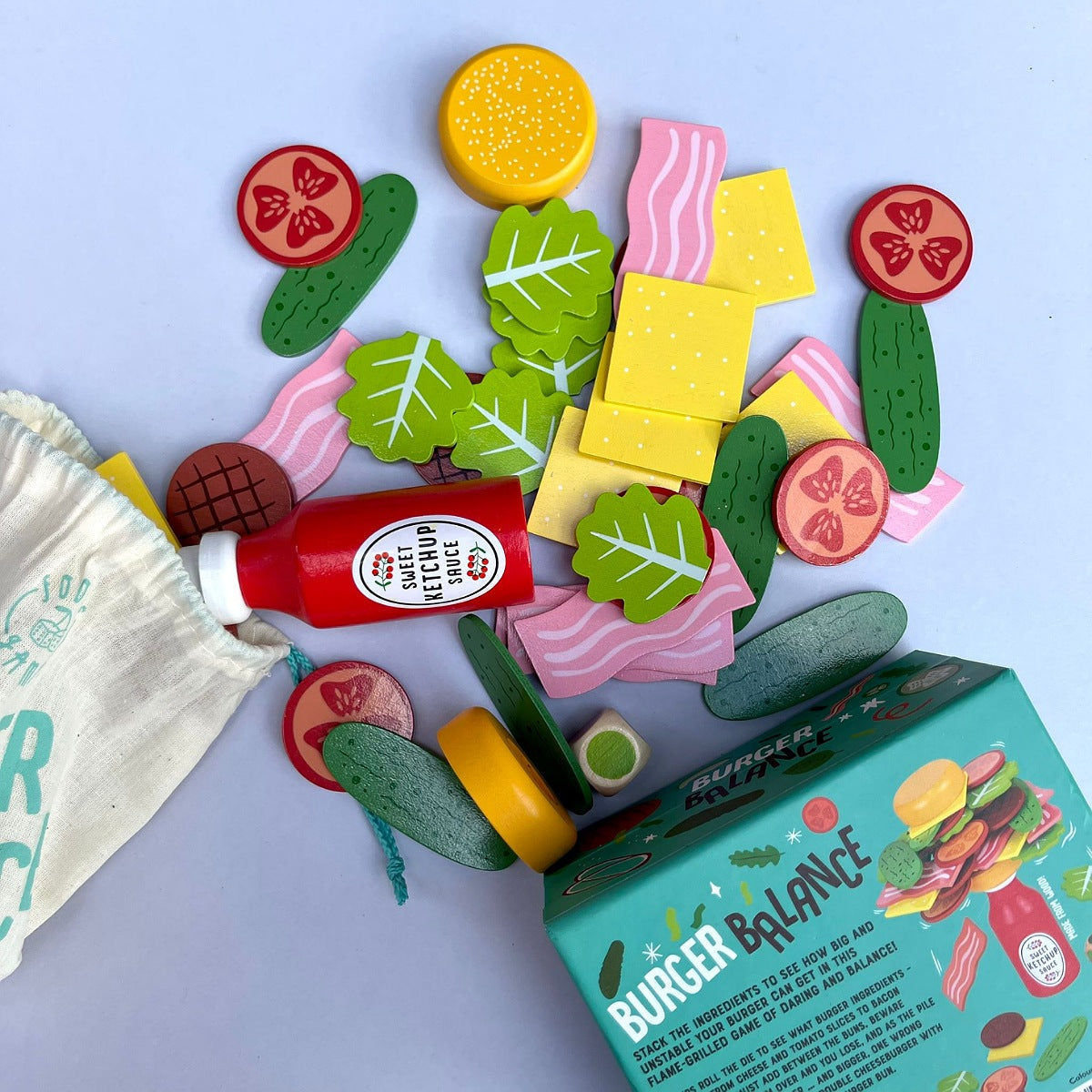 Colorful toy food items including vegetables, meat, and a bottle on a blue background with 'Burger Balance' packaging.
