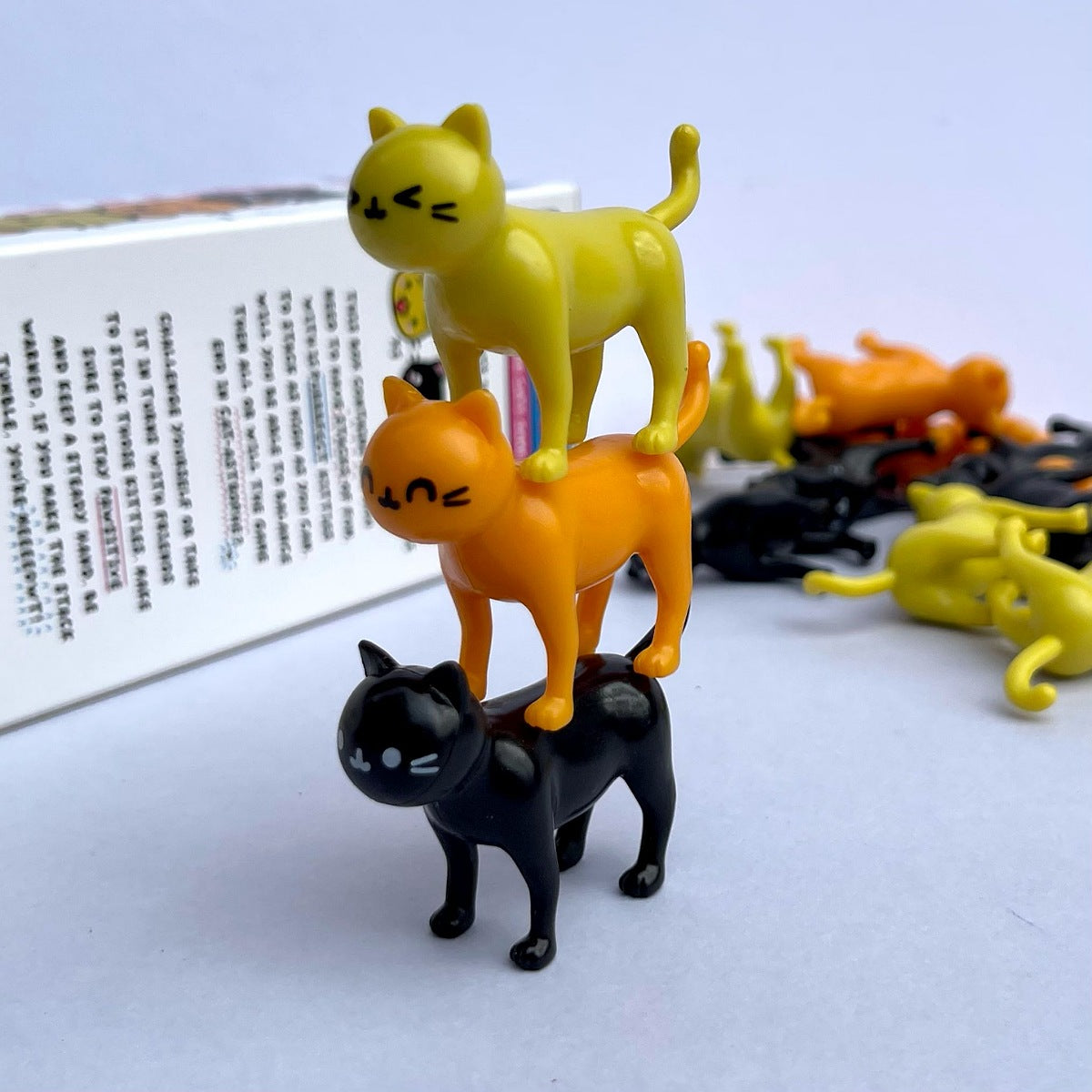 Stack of cat-shaped bookmarks in yellow, orange, and black on a white surface with text.