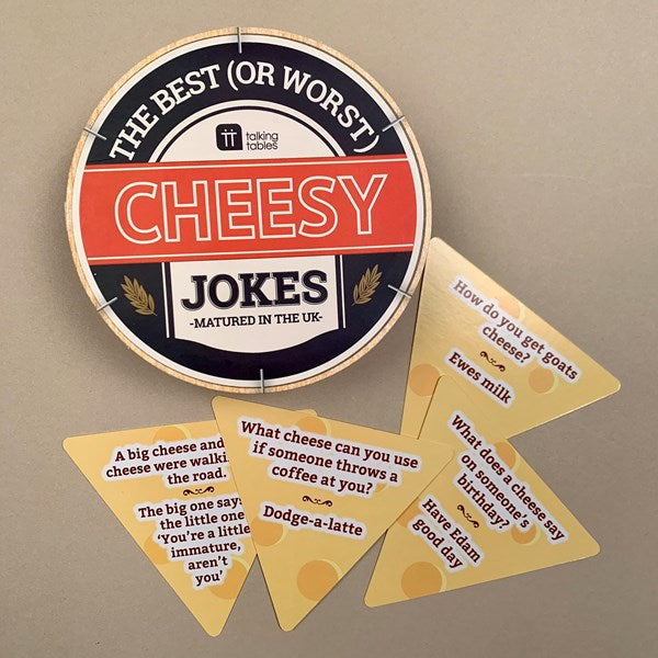 A round wooden sign and five triangular wooden joke cards for 'Cheesy Jokes' by Taking Tazell, displayed on a neutral beige background.