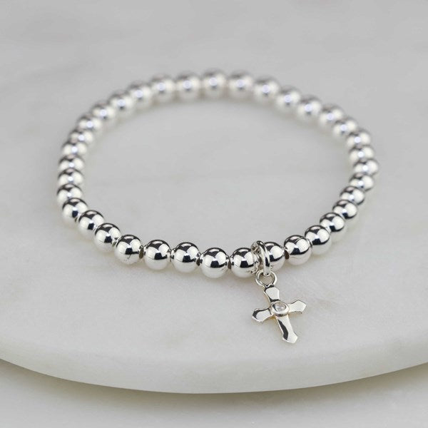 Silver beaded bracelet with a cross charm on a light gray background