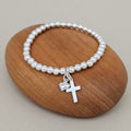 Silver bracelet with a cross and heart charm on a wooden rock