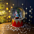 Decorative snow globe with Christmas scene and nutcracker soldier on a wooden surface with festive background