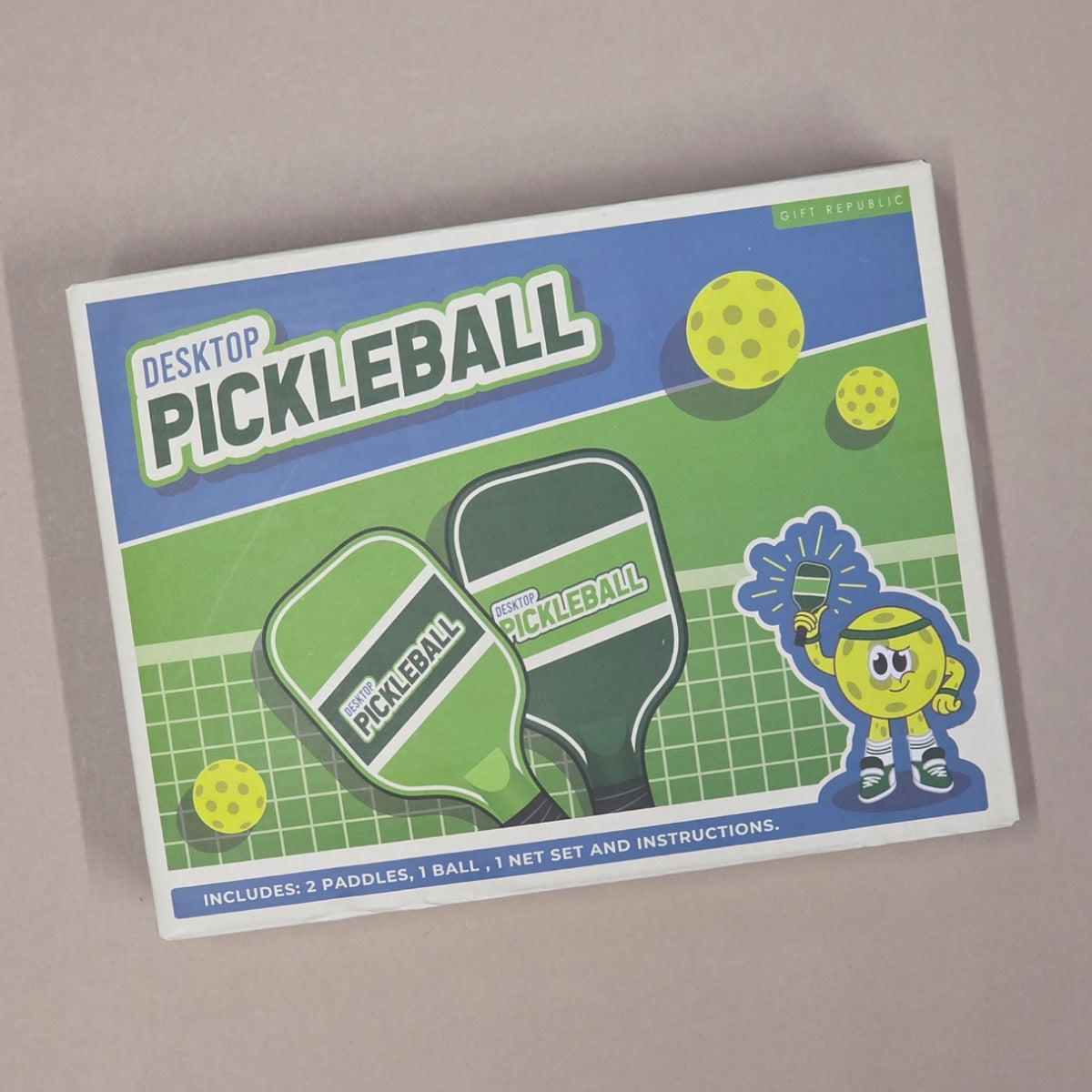 Packaging of Desktop Pickleball set with paddle graphics and text on a beige background