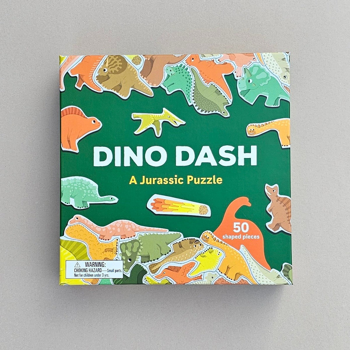 Box of 'Dino Dash' puzzle with dinosaur illustrations on a grey background
