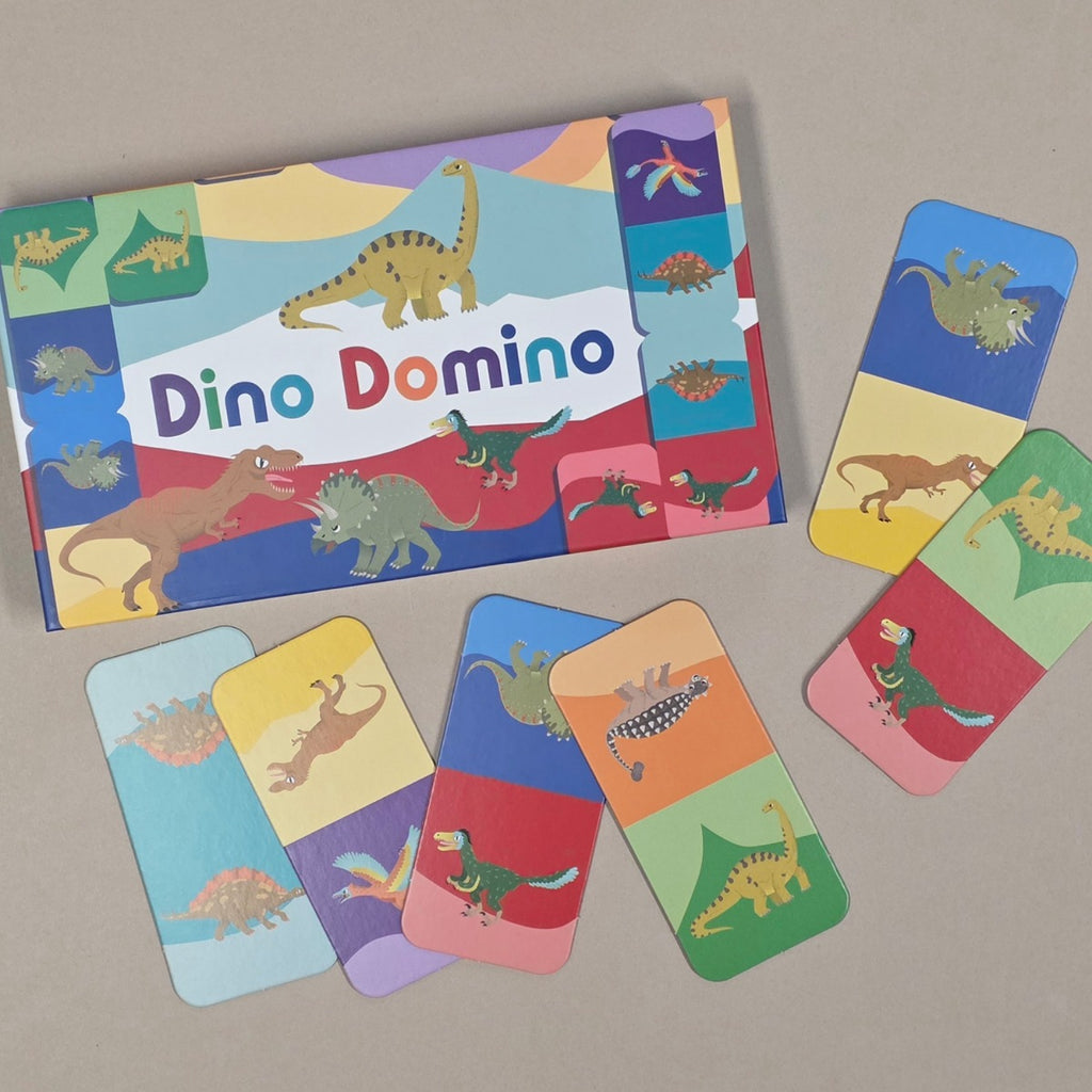 Dino Domino game set with colorful dinosaur-themed cards on a beige background