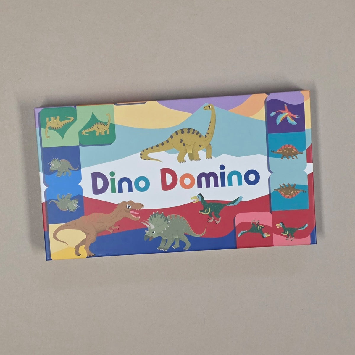 Dino Domino toy box with colorful dinosaur illustrations on a beige background