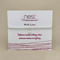 A silver beaded bracelet with a small heart-shaped crystal charm, displayed on a white card from the brand 'nest' with the message 'With Love' and 'Distance means nothing when someone means everything'.