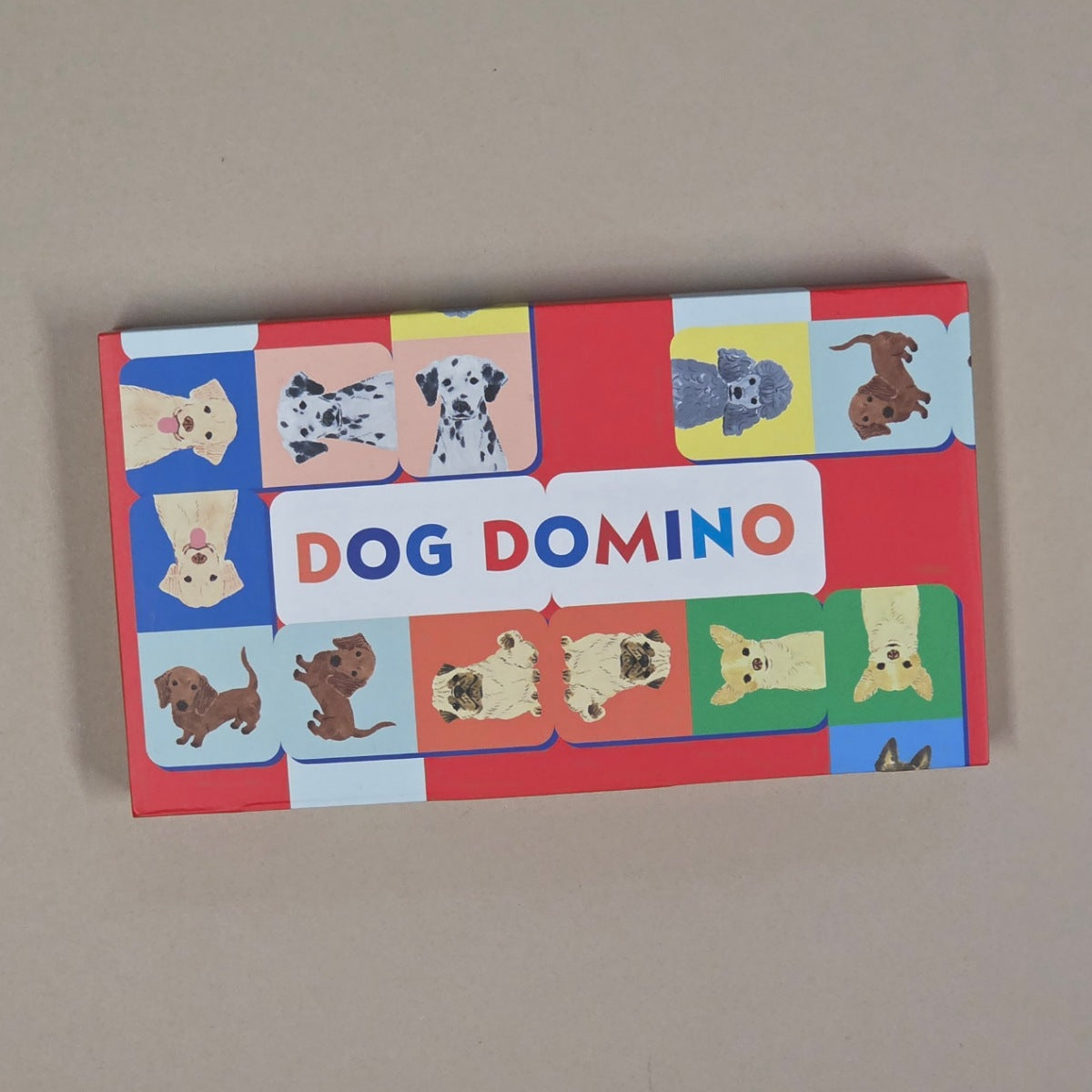 Box of 'Dog Domino' game with various dog illustrations on a beige background