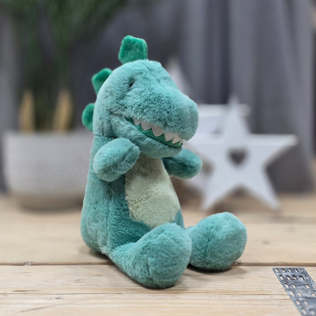 Plush dinosaur toy on a wooden floor with a blurred background