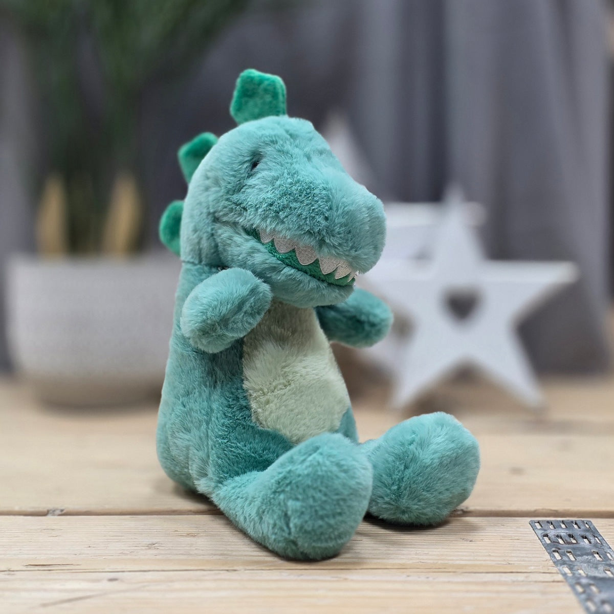 Plush dinosaur toy on a wooden floor with a blurred background