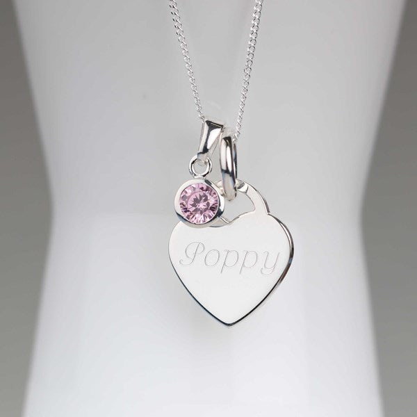 A silver heart-shaped pendant necklace engraved with the name 'Poppy' and featuring a small round pink gemstone charm, displayed on a white jewelry bust.