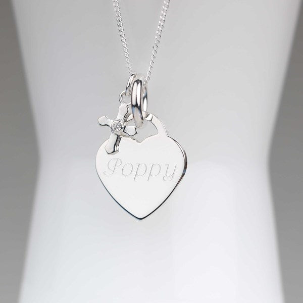A silver heart-shaped pendant necklace engraved with the name 'Poppy', hanging from a delicate silver chain on a white display stand.