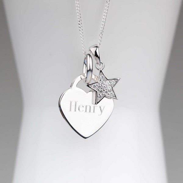 A silver necklace with a heart-shaped pendant engraved with the name 'Henry' and a small star charm, displayed on a white mannequin bust.