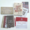 Collection of 'Escape from the Museum' game components including books and a pencil on a white background.