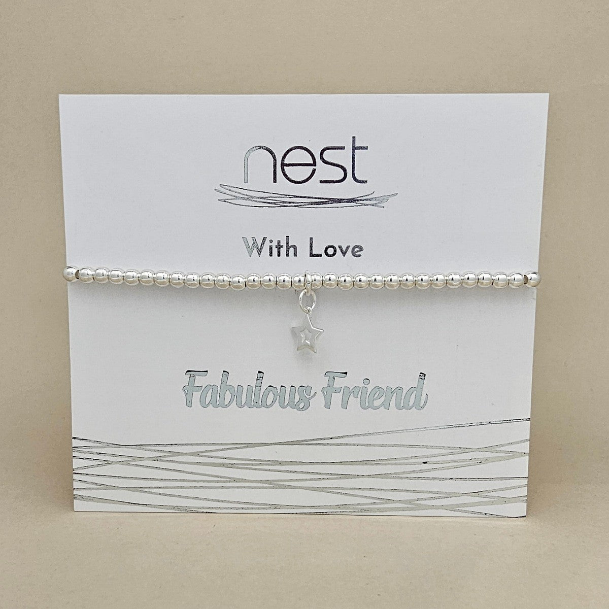A silver beaded bracelet with a dangling star charm, displayed on a white card that reads 'nest With Love Fabulous Friend' against a beige background.