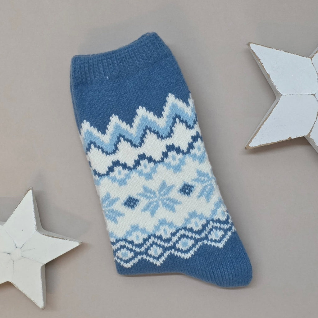Blue knitted sock with white Fair Isle pattern on a grey background