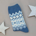 Blue knitted sock with white Fair Isle pattern on a grey background