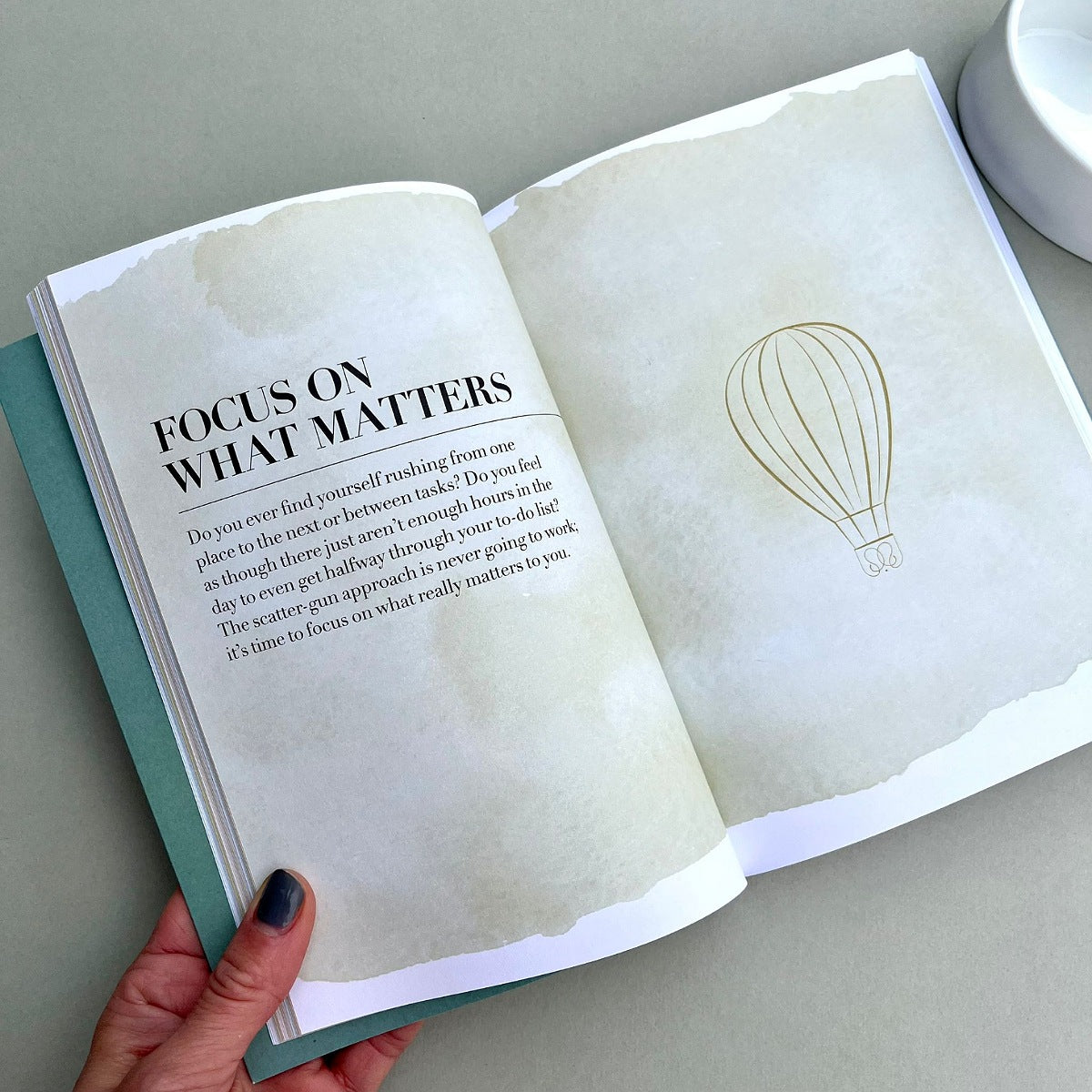 Open book with text entitled 'focus on what matters' and a hot air balloon illustration on a light grey background