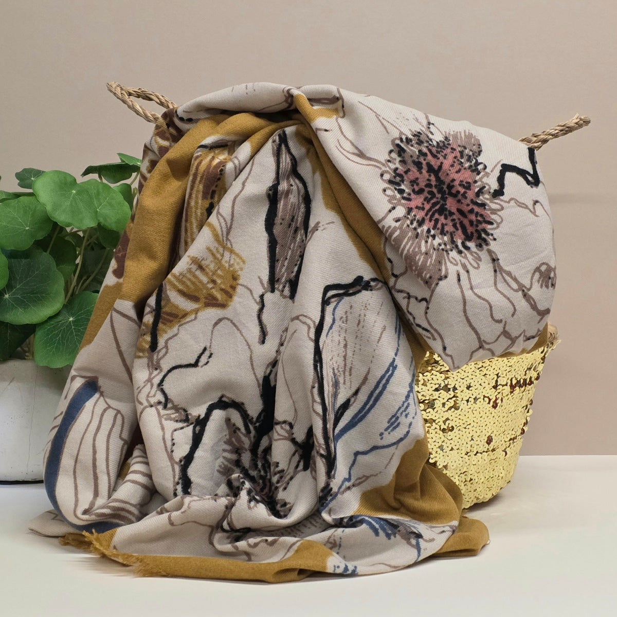 Decorative mid weight scarf with floral patterns in a decorative basket on a light background