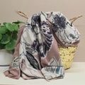 Floral-patterned mid weight scarf draped over a decorative basket with a plant in the background