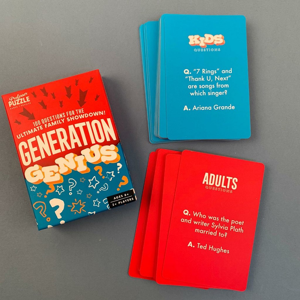 Generation Genius card game set on a grey surface, showing the red and blue box, a stack of blue question cards for kids, and several red adult question cards.
