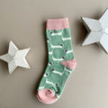 A single mint green sock with a repeating pattern of white sausage dogs with grey ears.  Featuring a pink cuff, heal and toe, displayed on a neutral beige background with white star-shaped props.
