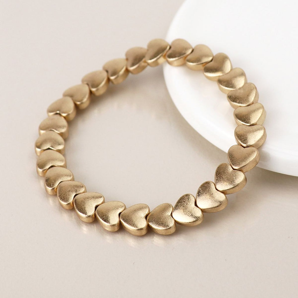 Matt gold linking heart-shaped bracelet on a light background