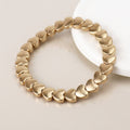 Matt gold linking heart-shaped bracelet on a light background