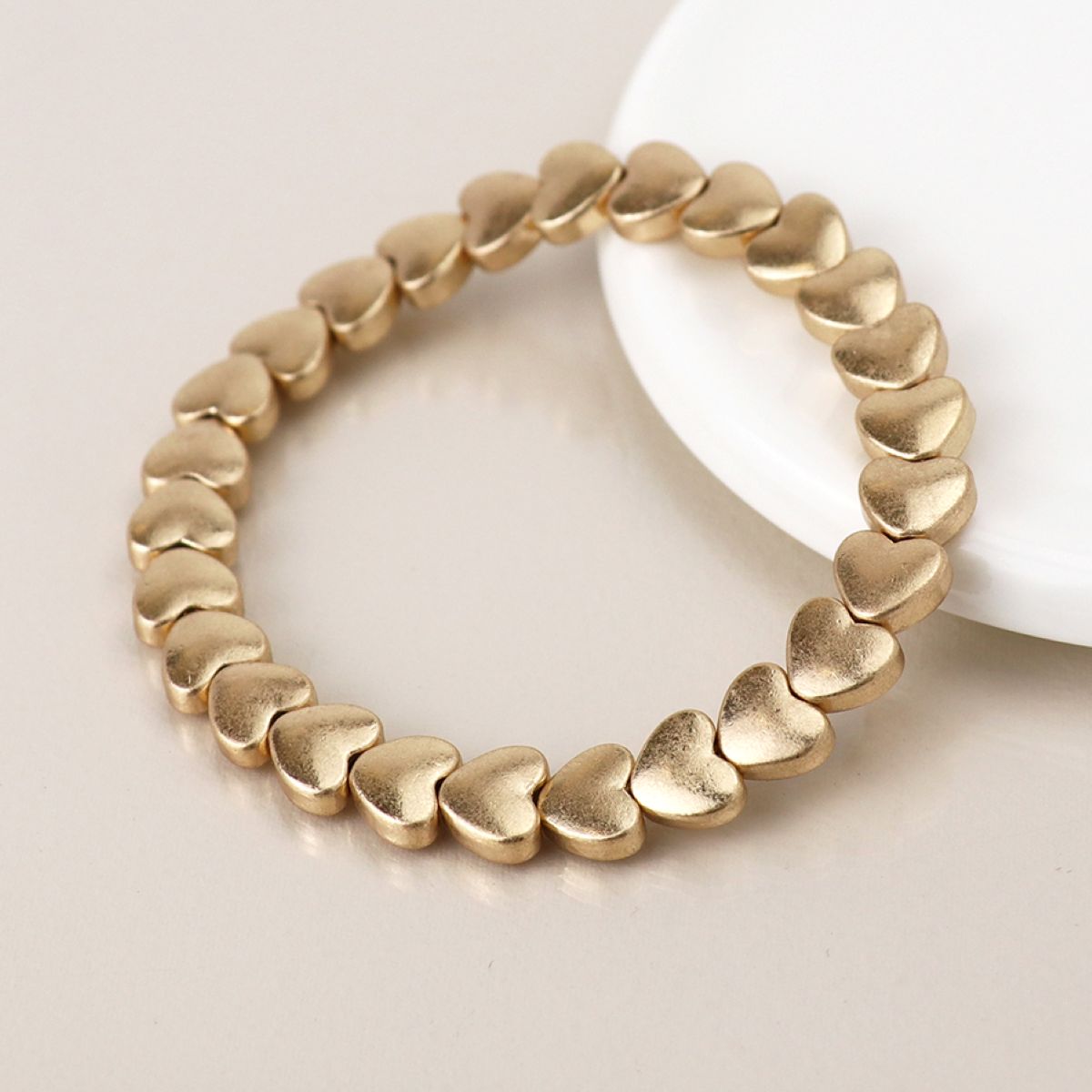 Matt gold linking heart-shaped bracelet on a light background