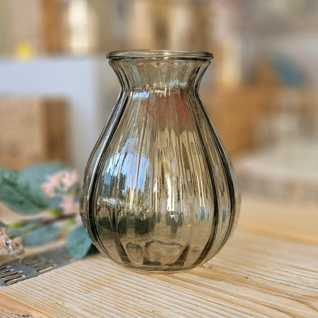 Glass ribbed vase on a wooden surface with a blurred background